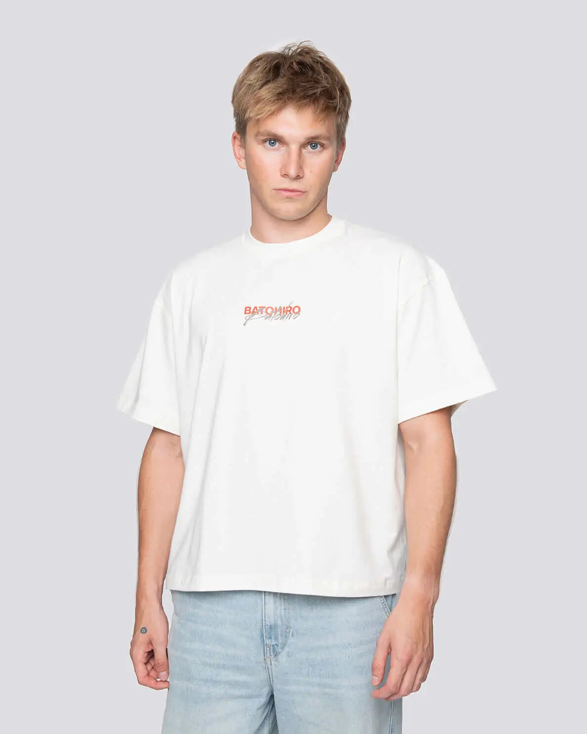 Mladý muž nosící bílé tričko s originálním designem Batohiro, ideální pro stylový dárek.