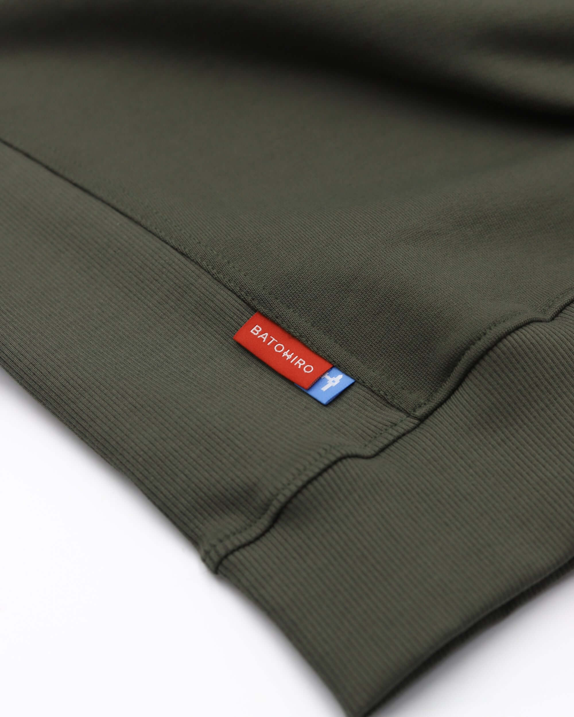 Detail of Batohiro 343 – Mikina Crewneck Green showing logo tag on the cuff.