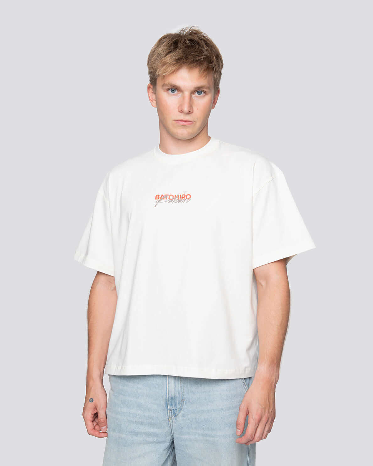 Mladý muž nosící bílé tričko s originálním designem Batohiro, ideální pro stylový dárek.