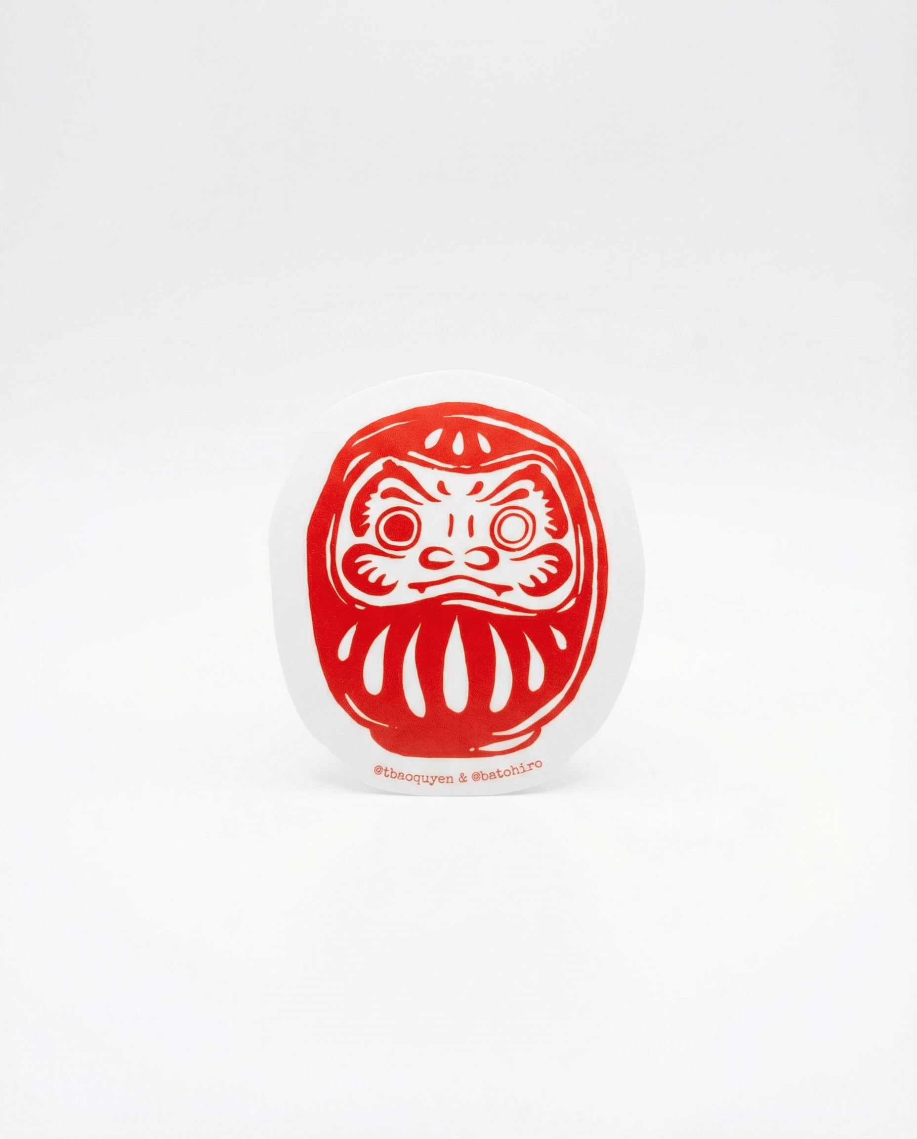 Batohiro® Daruma Sticker design featuring a red and white daruma face illustration by Bao Quyen.