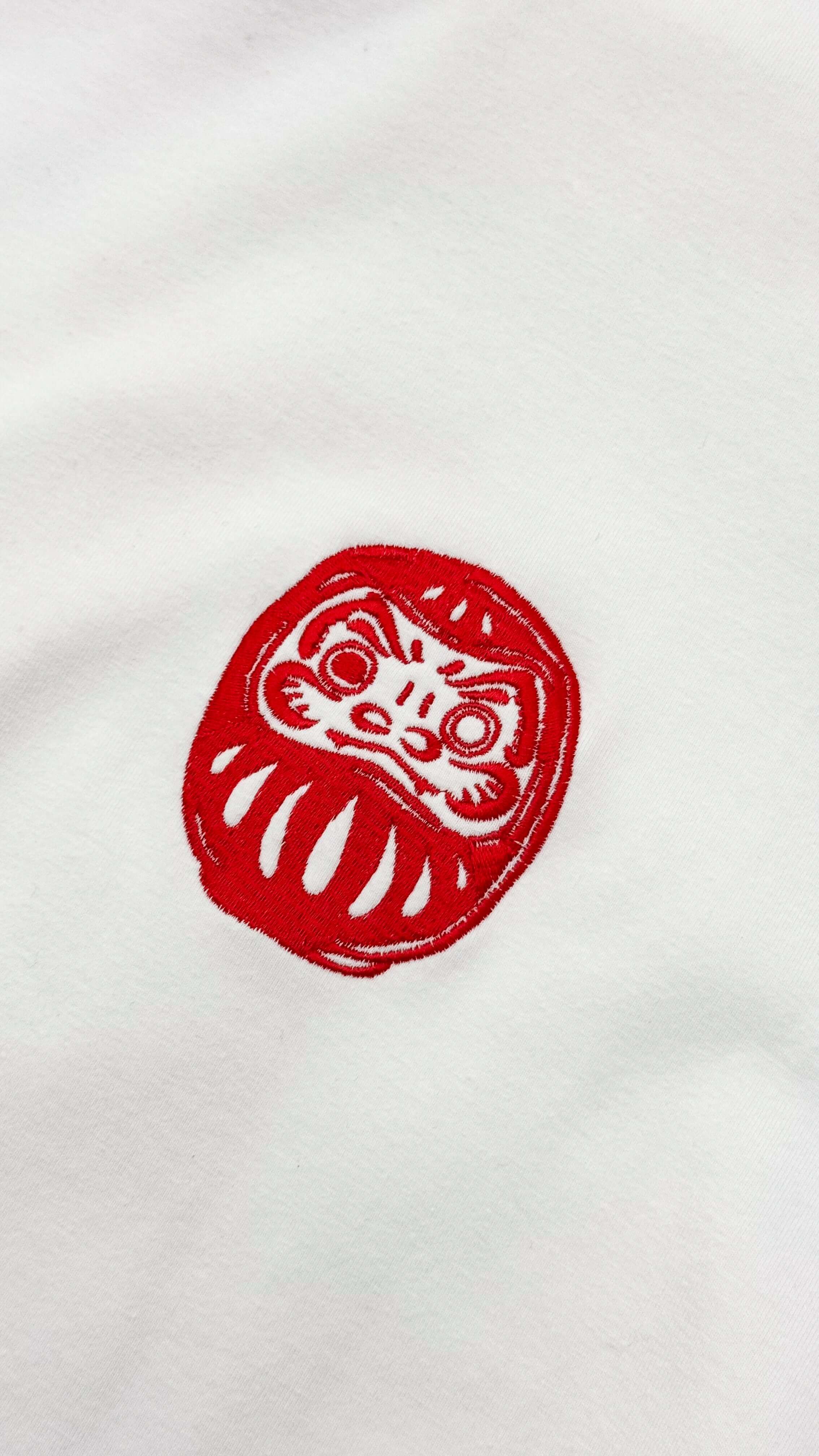 Detail of the red Daruma embroidery on the Daruma - White Cropped Oversized Tee.
