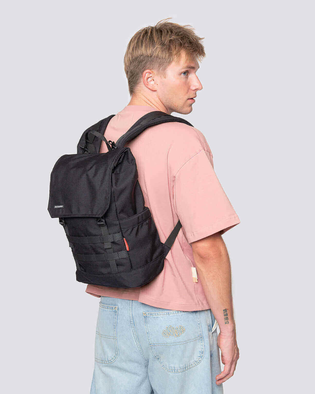 Young man wearing a black Minato Lite backpack, showcasing its sleek design and adjustable straps.