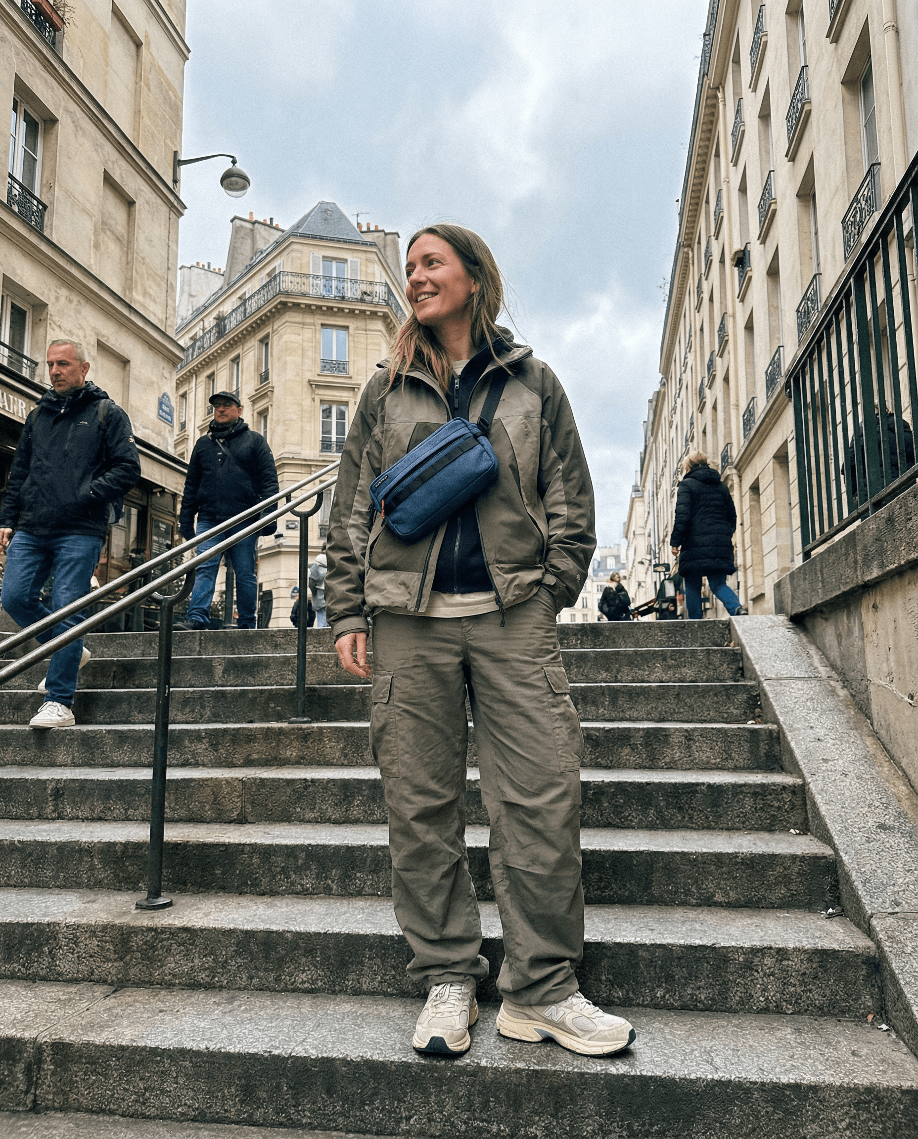 Osoba v přírodním oblečení se zavazadlem Kai - Blue Denim na schodech ve městě.