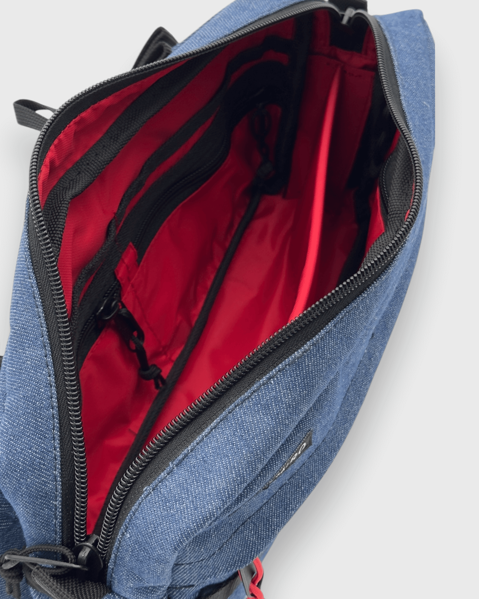 Interior view of the Kai Blue Denim bag, featuring red lining and multiple organizational pockets.