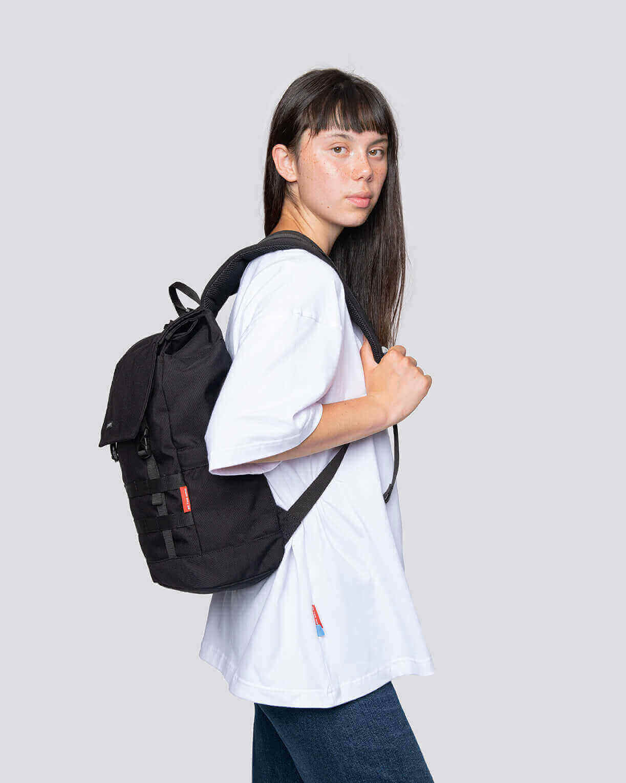 Stylish young woman showcasing the Minato Lite backpack in black, perfect for daily use and weekend adventures.